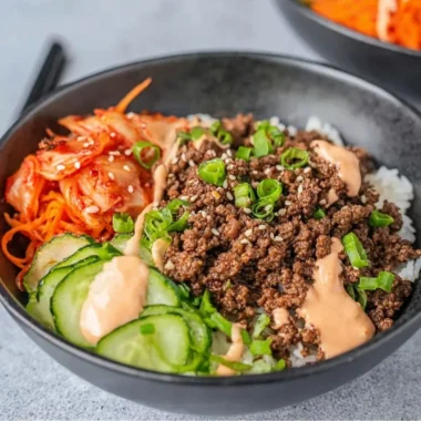 Korean Beef Rice Bowl topped with fresh vegetables and garnished with sesame seeds
