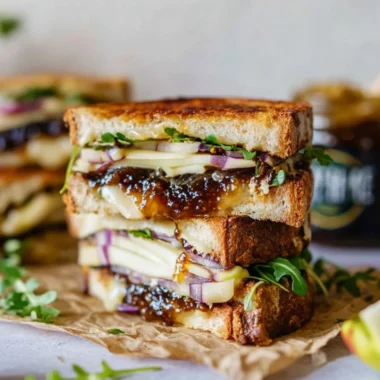Gourmet brie, fig, and apple grilled cheese sandwich on a plate.