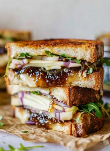 Gourmet brie, fig, and apple grilled cheese sandwich on a plate.