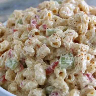 Creamy macaroni salad in a bowl, garnished with herbs