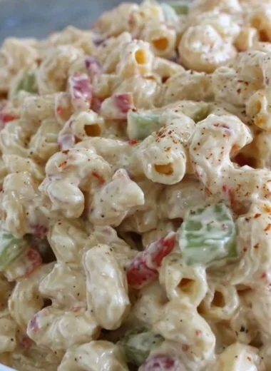 Creamy macaroni salad in a bowl, garnished with herbs