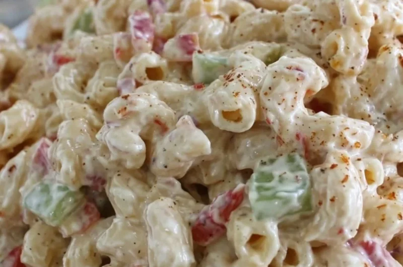 Creamy macaroni salad in a bowl, garnished with herbs