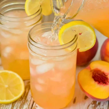 Refreshing homemade peach lemonade served in a glass with peaches