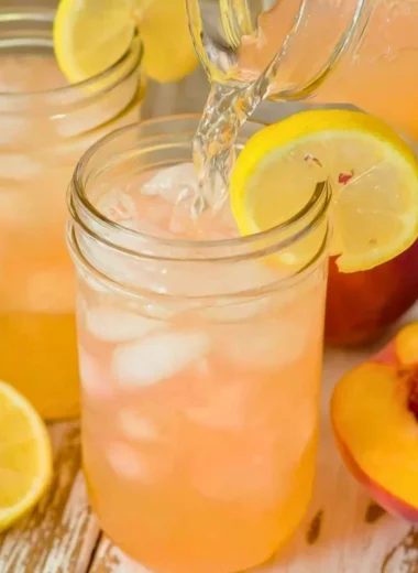 Refreshing homemade peach lemonade served in a glass with peaches