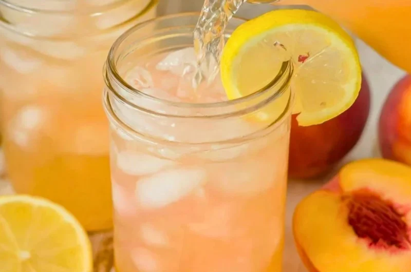 Refreshing homemade peach lemonade served in a glass with peaches