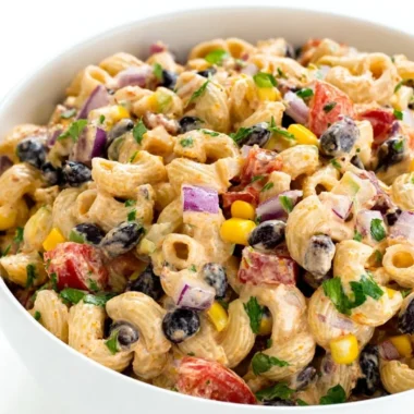 A colorful Mexican Pasta Salad with vegetables and dressing in a bowl.