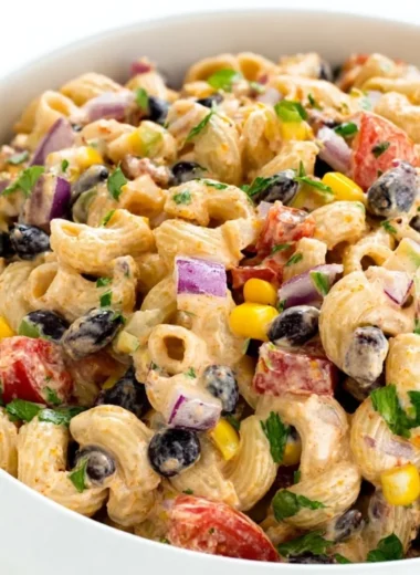 A colorful Mexican Pasta Salad with vegetables and dressing in a bowl.
