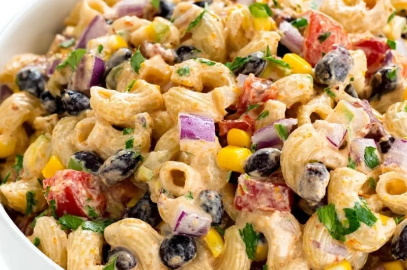 A colorful Mexican Pasta Salad with vegetables and dressing in a bowl.