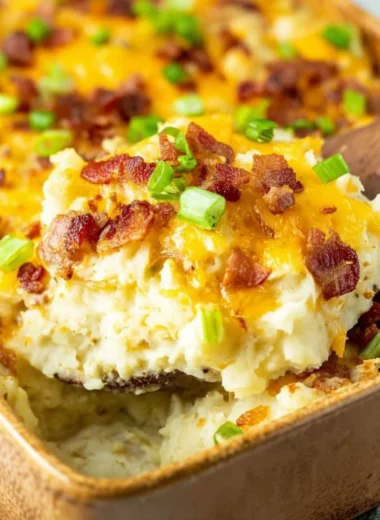 Twice baked potato casserole topped with cheese and chives in a baking dish