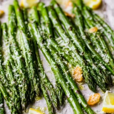 Oven roasted garlic parmesan asparagus on a plate garnished with herbs.