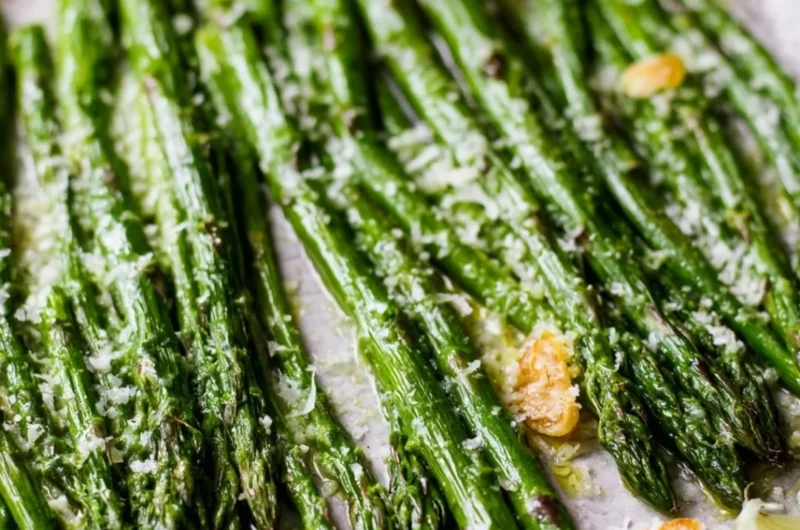 Oven roasted garlic parmesan asparagus on a plate garnished with herbs.