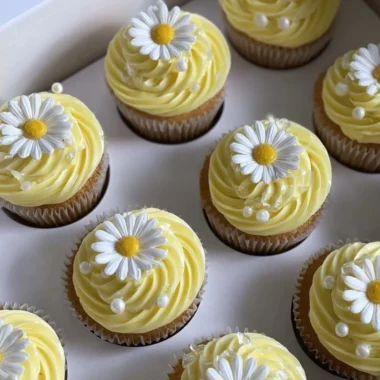 Pastel yellow cupcakes decorated with daisies and pearls for a charming dessert
