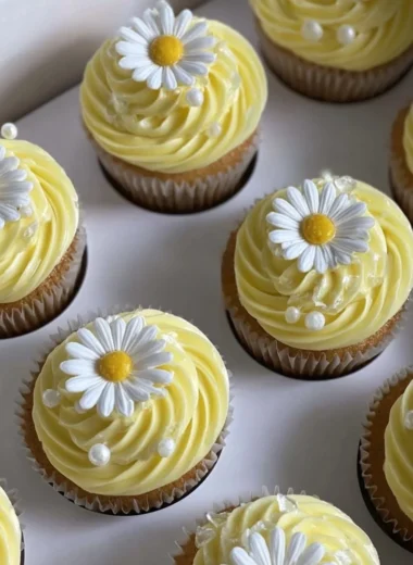 Pastel yellow cupcakes decorated with daisies and pearls for a charming dessert