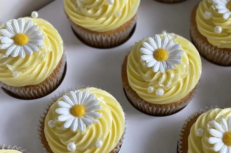 Pastel yellow cupcakes decorated with daisies and pearls for a charming dessert