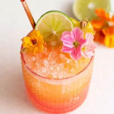Colorful glass of Pineapple Mango Rum Punch garnished with fruit slices