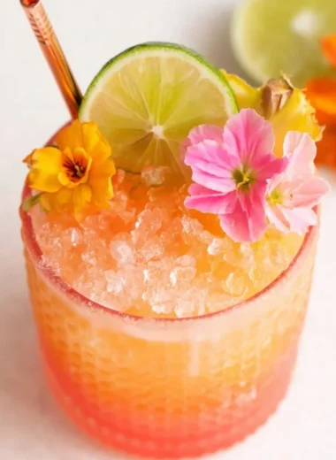 Colorful glass of Pineapple Mango Rum Punch garnished with fruit slices