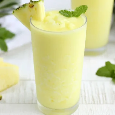 Refreshing Pineapple Rum Slush drink served in a glass with ice and garnished with a slice of pineapple.