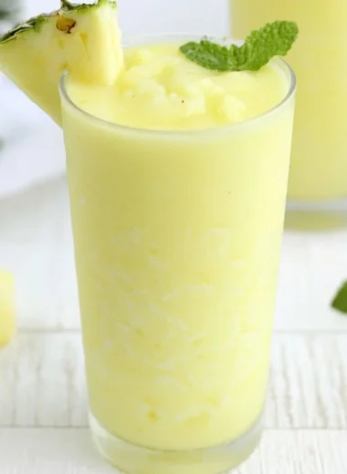 Refreshing Pineapple Rum Slush drink served in a glass with ice and garnished with a slice of pineapple.