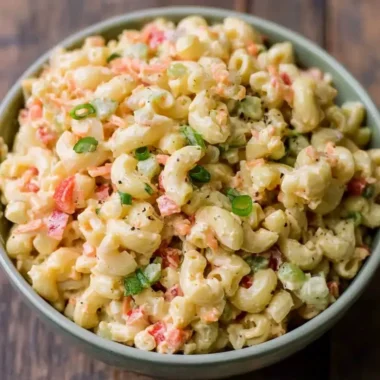 Small homemade macaroni salad served in a bowl with fresh vegetables.