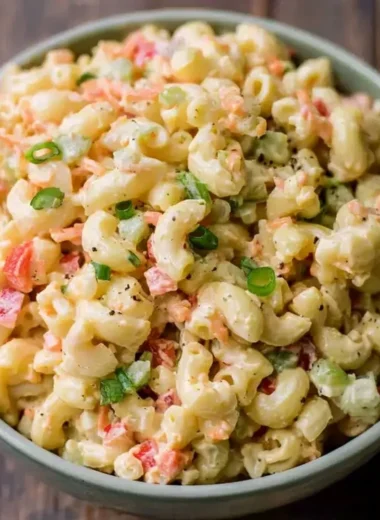 Small homemade macaroni salad served in a bowl with fresh vegetables.