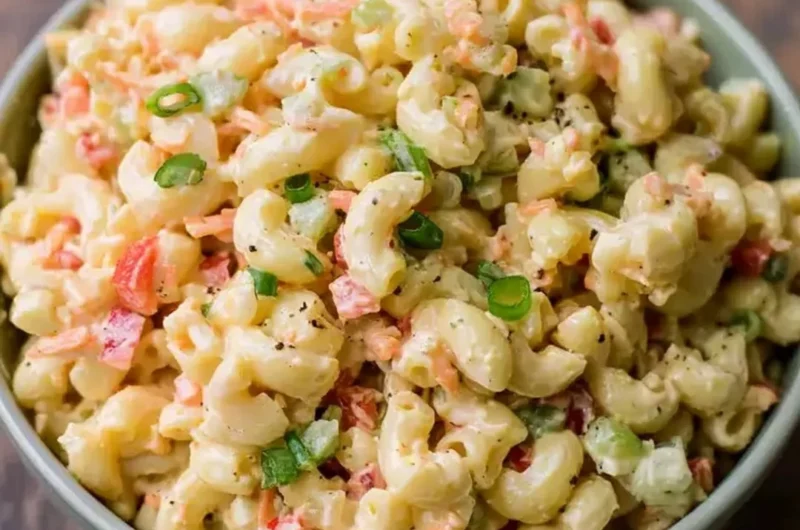 Small homemade macaroni salad served in a bowl with fresh vegetables.