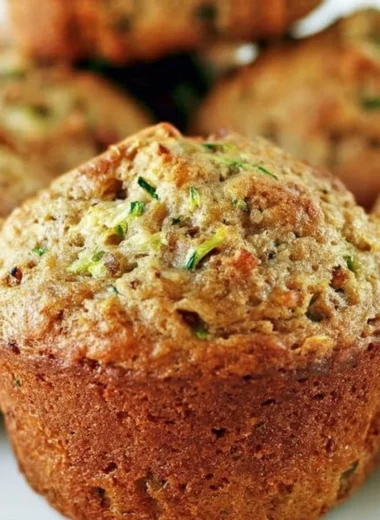 Freshly baked zucchini bread muffins on a wooden table.