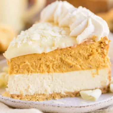 A delicious slice of cozy eggnog pumpkin cheesecake topped with whipped cream.