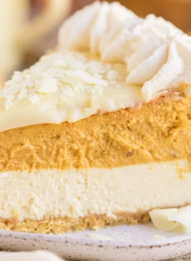 A delicious slice of cozy eggnog pumpkin cheesecake topped with whipped cream.