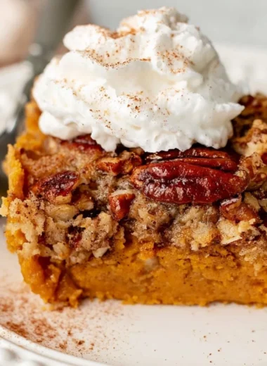 Cozy pumpkin dump cake served in a dish, topped with whipped cream.