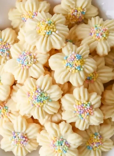 Batch of homemade Lemon Spritz Cookies decorated with lemon zest.