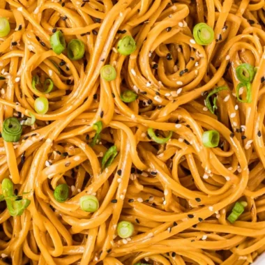 Plate of savory sesame noodles with vegetables and sesame seeds garnished