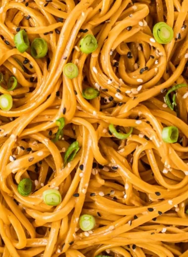 Plate of savory sesame noodles with vegetables and sesame seeds garnished