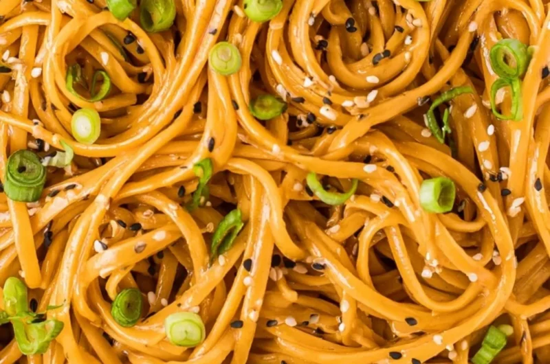 Plate of savory sesame noodles with vegetables and sesame seeds garnished