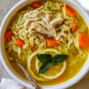 Bowl of Chicken Lemon Orzo Soup garnished with herbs and lemon slices