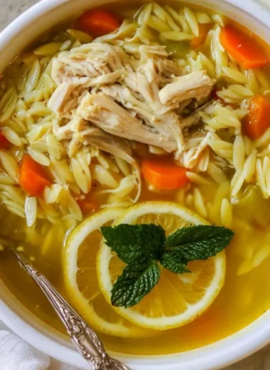 Bowl of Chicken Lemon Orzo Soup garnished with herbs and lemon slices